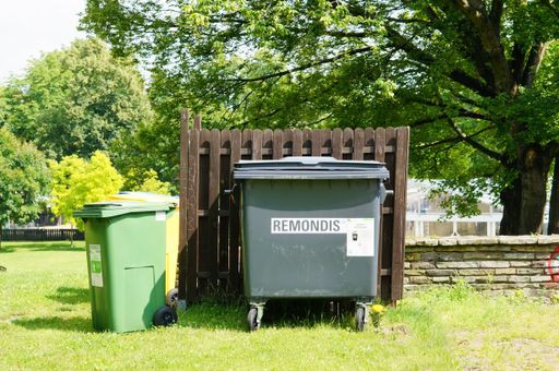 The "Remondis" garbage container with a logo on green grass in the city center, Poznan, Poland