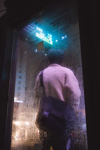 A man in a pink jacket standing under the rain at night in South Korea