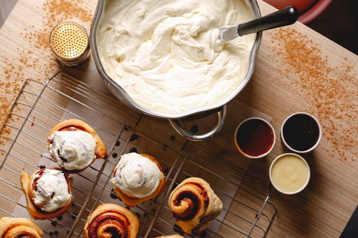 A closeup shot of hot, delicious Cinnabons on the table and a bowl with cream next to them