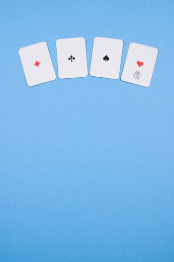A vertical shot of four playing cards isolated on a blue background