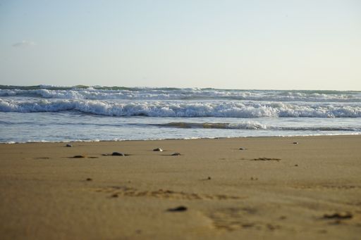 A close-up shot of a beautiful sea with foamy waves rolling and crashing on a sandy beach