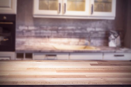 A closeup shot of a wooden table in a kitchen with drawers as a background