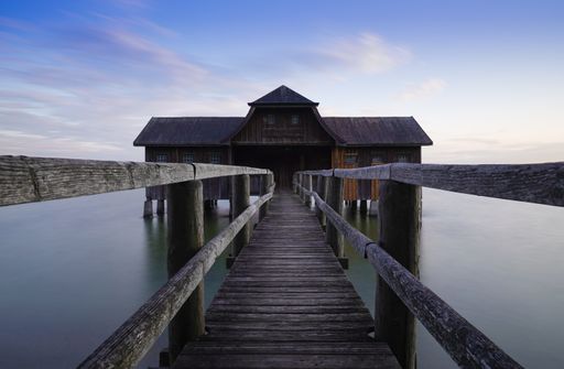 A closeup shot of a wooden deck and a house in the water on a sunny day
