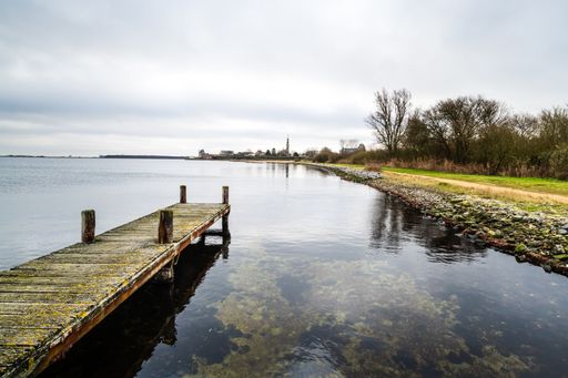 An old pier on the Lake Veere surrounded by greenery under the cloudy sky in the Netherlands
