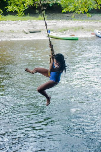 A vertical shot of a Hispanic woman jumping into the lake