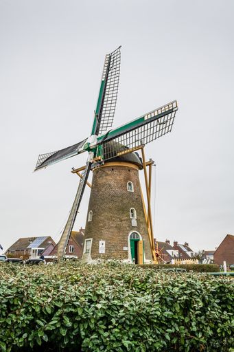 A vertical picture of an old windmill under a cloudy sky in Zeeland in the Netherlands