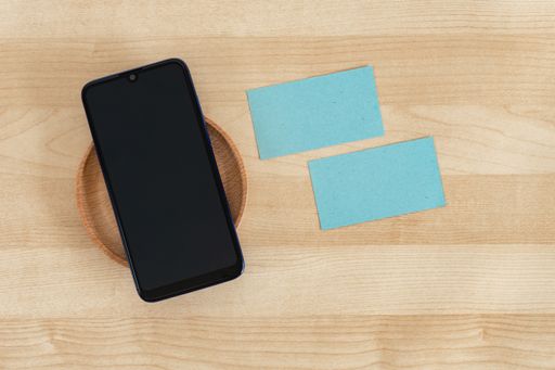 A top view of blank business cards and a smartphone on a wooden office table, recycled paper