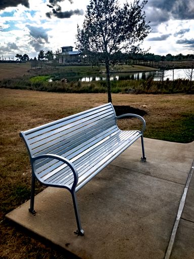 A vertical shot of an empty metal bench at the park in Katy, United States