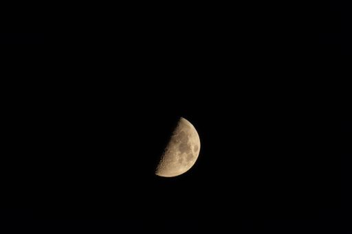 A quarter moon isolated on a dark black sky background