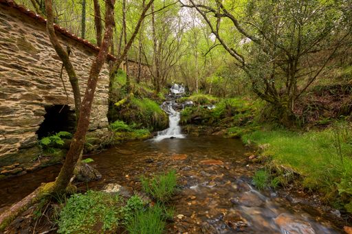 A scenic view of a small waterfall next to an old water mill in the area of Galicia, Spain