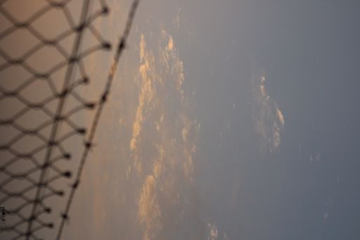 A sky at the sunset and a part of metal fence in the left side