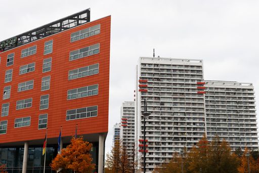 Modern urban architecture with a red office building and high-rise towers in Berlin under a cloudy sky