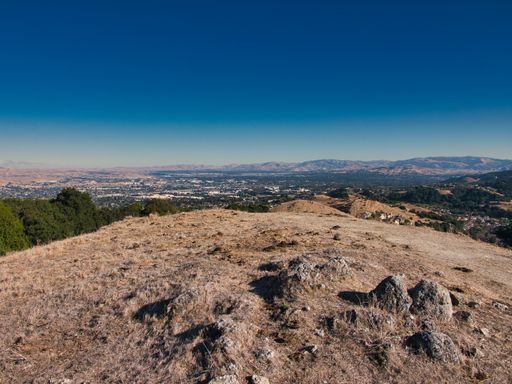 A scenic view of a hilltop on a blue sky background