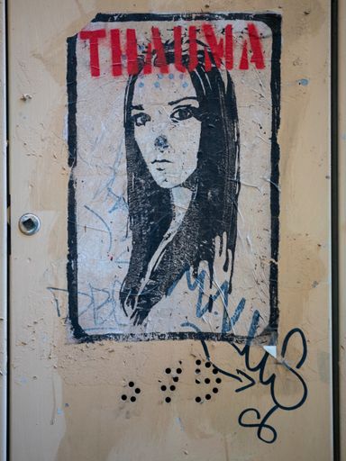 A vertical shot of an old poster with graffiti on a wall in Lucca, Tuscany, Italy