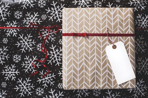 A closeup shot of a wrapped Christmas gift box with a white tag as a space for your text