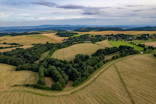 An aerial shot of mountain green forests and agricultural fields in a rural area