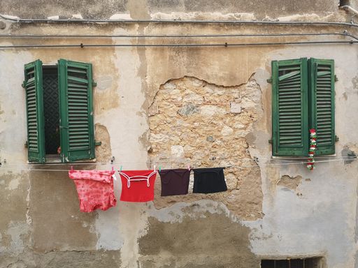 A closeup of the laundry drying on ropes on an old building with wooden windows