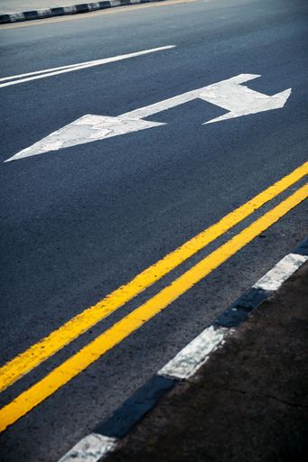 Road with double yellow lines and white arrows indicating a split