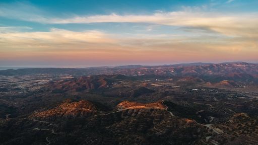 Aerial view of a vast mountainous landscape at sunset with vibrant skies, capturing the beauty of nature's colors and contours.