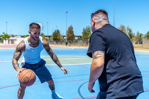 A view of sporty Caucasian males with tattoos playing basketball