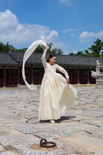 A South Korean young woman dancing in traditional Hanbok dress in Gyeongbokgung Palace, South Korea