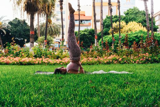 An adult Spanish woman doing the yoga Sarvangasana pose on a mat in a park