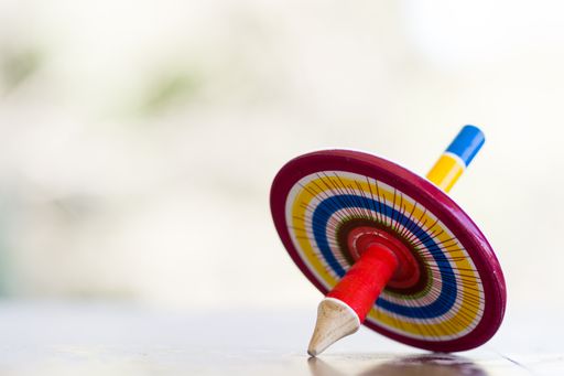 A colorful wooden peg-top or a teetotum on a blurred background