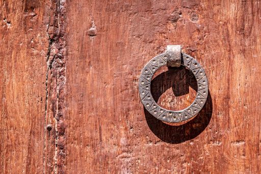 A closeup shot of an old metallic door knocker on a wooden door