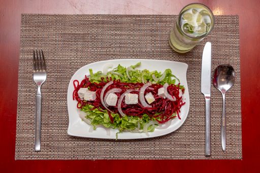 An overhead shot of fresh beet salad with cheese on a white ceramic plate