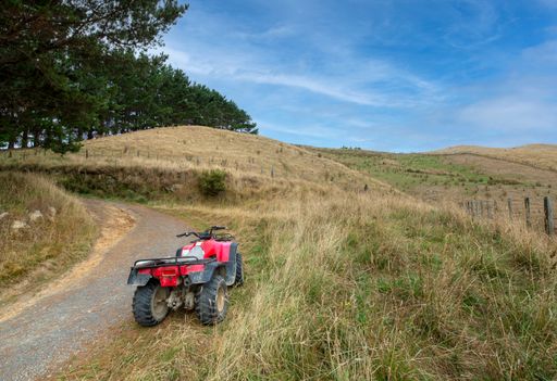 The farmland in the rolling hills around the Ohariu Valley near Wellington in New Zealand. The Honda farm bike has had the logo removed