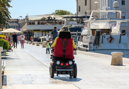 An old man in a wheelchair in the middle of the promenade in the city of Split, Croatia