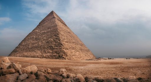 The Great Pyramid of Giza under a partly cloudy sky, showcasing its ancient architecture