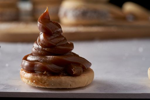 A closeup of caramelized milk on alfajor on a wooden board in the kitchen