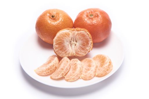 A plate of whole and peeled tangerines isolated on white background with free space for text