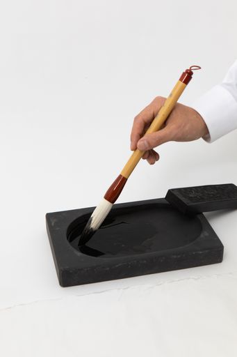 A vertical shot of a person holding a Korean traditional pen with some ink