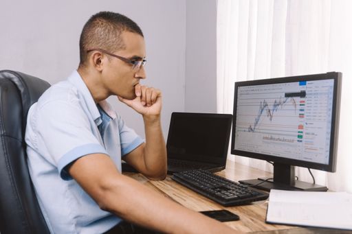 A closeup shot of a young Hispanic man viewing a graph on a computer in the office
