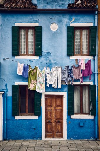 A beautiful vertical symmetric shot of a suburban blue building with clothes hanging on a rope