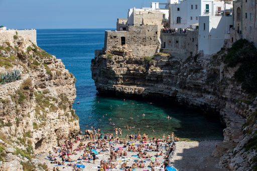 An aerial shot of people relaxing and swimming on lovely beach Lama Monachile in Polignano a Mare