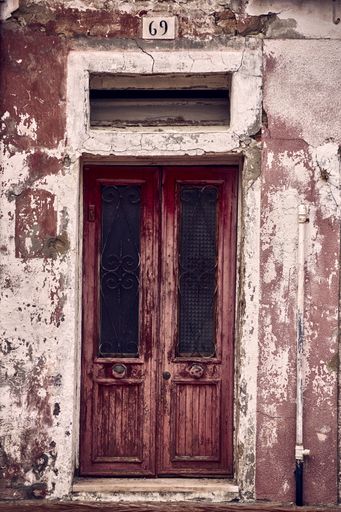 A vertical shot of an old wooden rusty weathered door of an abandoned office with grungy walls around