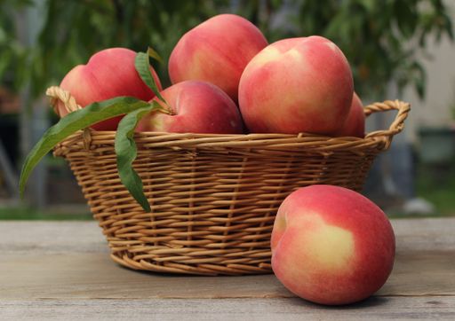 A basket of fresh organic peaches on a table at a farmers market