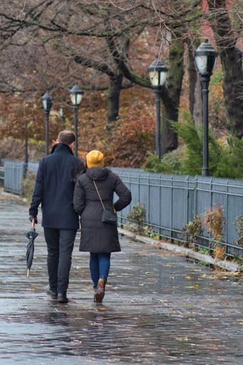 A couple walking arm in arm at the Brooklyn Heights Promenade, NY Waterfront captured on a rainy day
