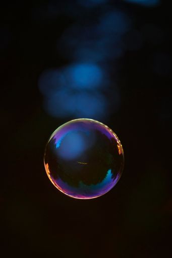A closeup shot of a floating soap bubble with dark blue background