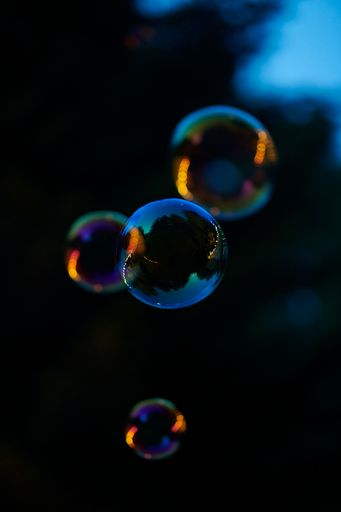 A closeup shot of floating soap bubbles with reflection on dark blue background
