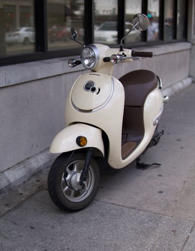 A vertical shot of a tan scooter parked on the sidewalk in Savannah, Georgia, USA