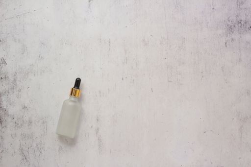A small glass bottle filled with oil on a rusty wall background - copy space