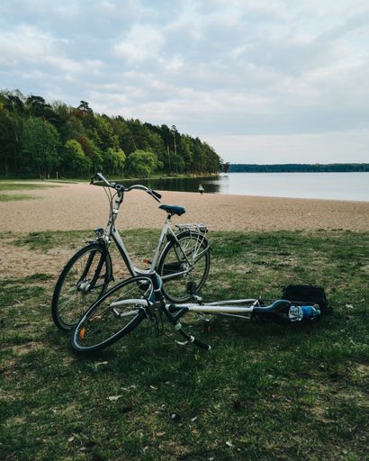 A shot of two bikes parked near the lake with a beautiful view of the forest
