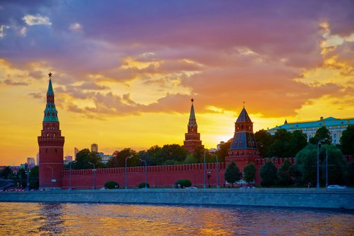 A vibrant sunset over the Kremlin in Moscow, Russia, with colorful skies and the Moskva River in the foreground.