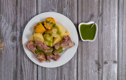 Food from the Canary Islands (Spain), consisting of a dish of salty ribs, boiled potatoes with ears of sweet corn covered with spicy green mojo