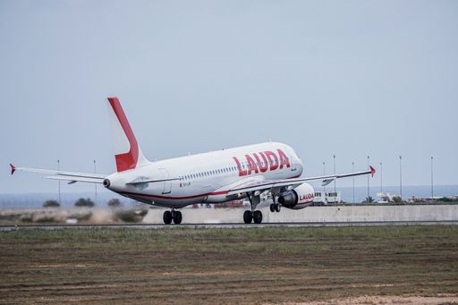 White plane with red letters of the Ryanair company and the Lauda serigraphy, taking off on the Alicante airport runway with sea in the background