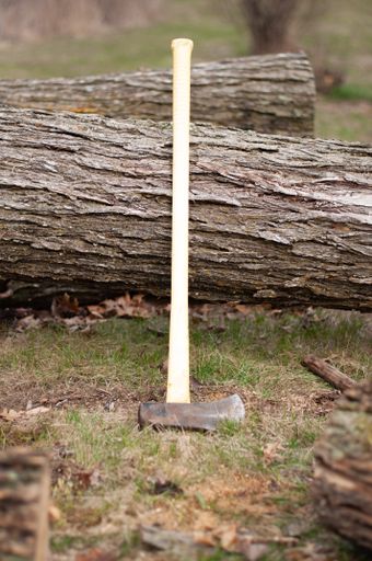 A vertical shot of an ax  on a piece of wood